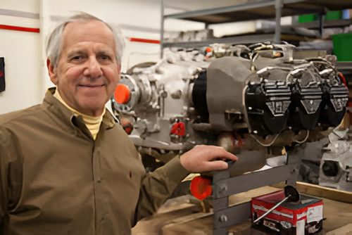Man in workshop with vintage car engines.