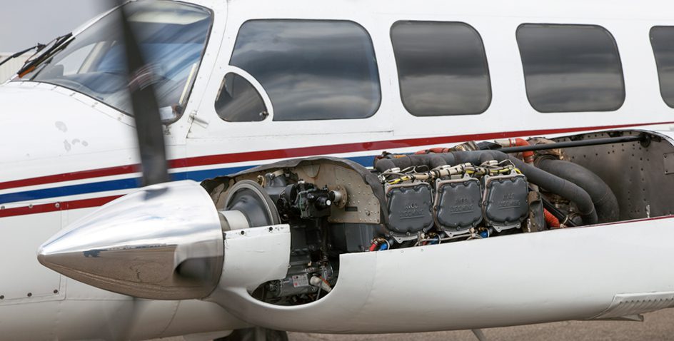 Close-up of a small aircraft with its engine exposed for maintenance.