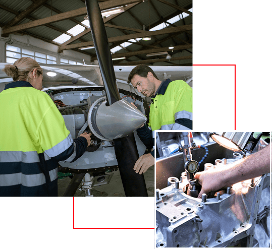 Two workers inspect an aircraft engine inside a hangar.